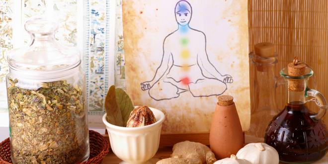 Traditional alternative therapy theme with medicinal herbs and oils with a watercolor of a silhouette of man with chakras in the background.