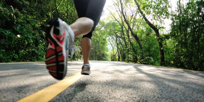 a woman running down a narrow road in the forest