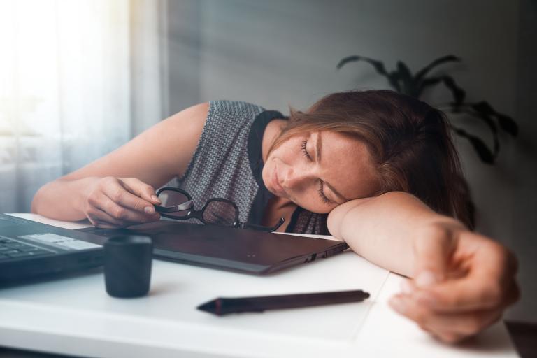 A young woman that has fallen asleep while working on her computer.