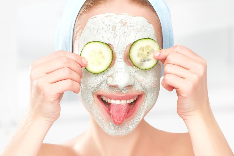 a woman with a facial mask and cucumbers over her eyes